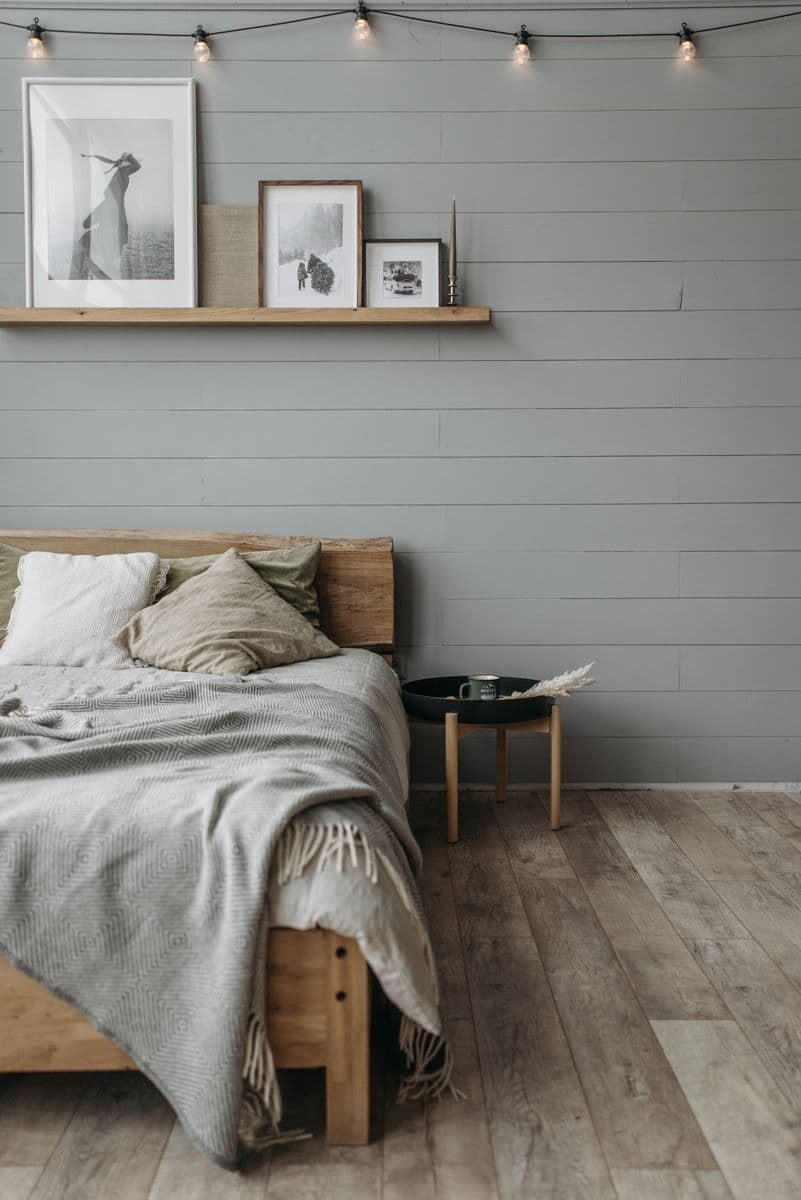 A wooden bed with layered bedding beside a small bedside table.